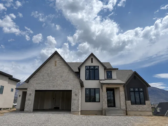 Contemporary exterior featuring a combination of stone veneer and stucco finishes, black-framed windows, a multi-car garage, and a covered entry with steps