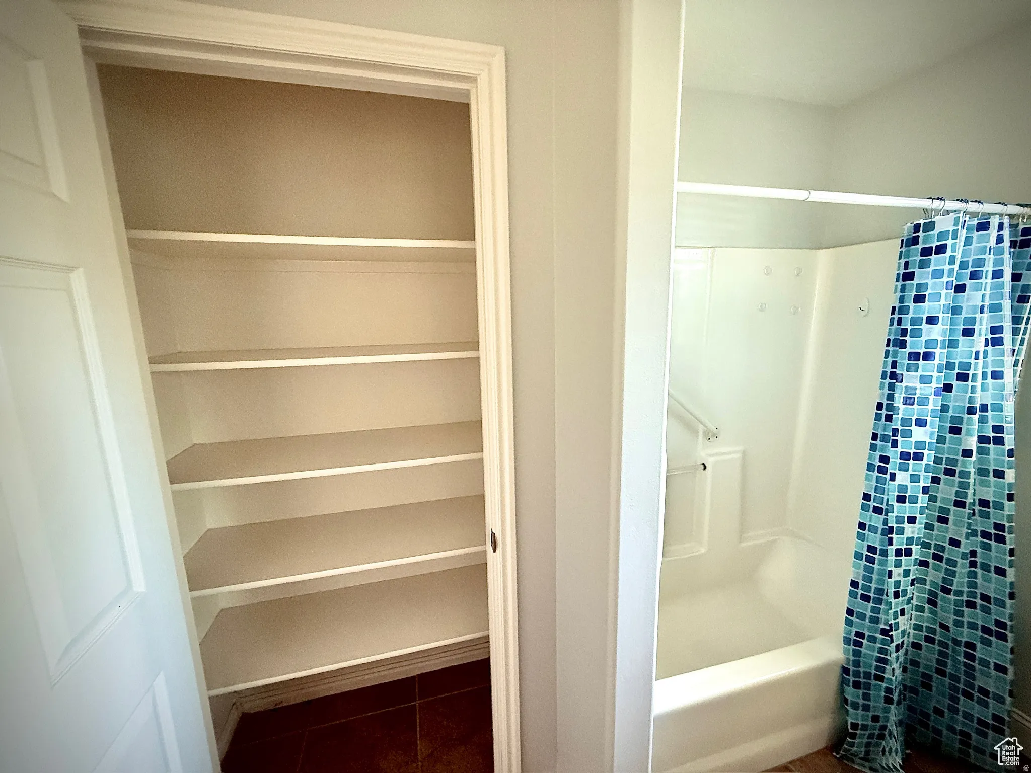 Full bath with dark tile patterned flooring, shower / bathtub combination with curtain, and a closet
