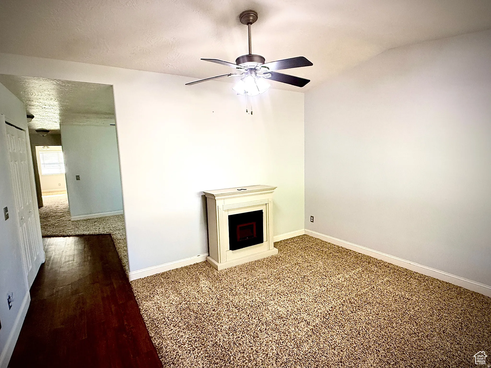 Unfurnished living room with a fireplace, a textured ceiling, and a ceiling fan