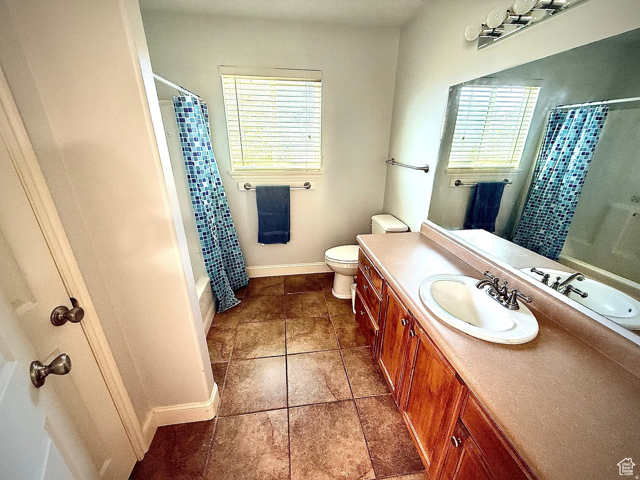 Full bath with vanity, shower / bathtub combination with curtain, and dark tile patterned flooring