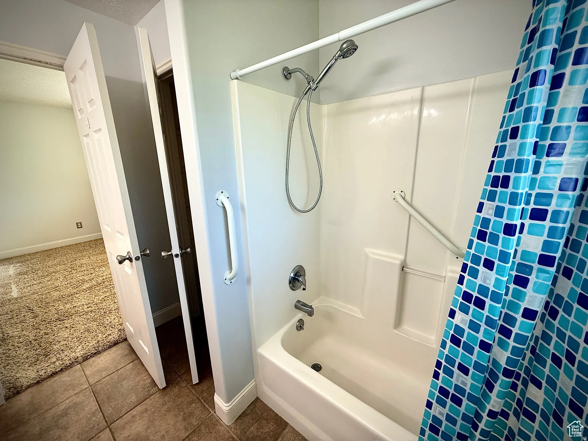 Bathroom featuring shower / tub combo, dark carpet, and dark tile patterned flooring