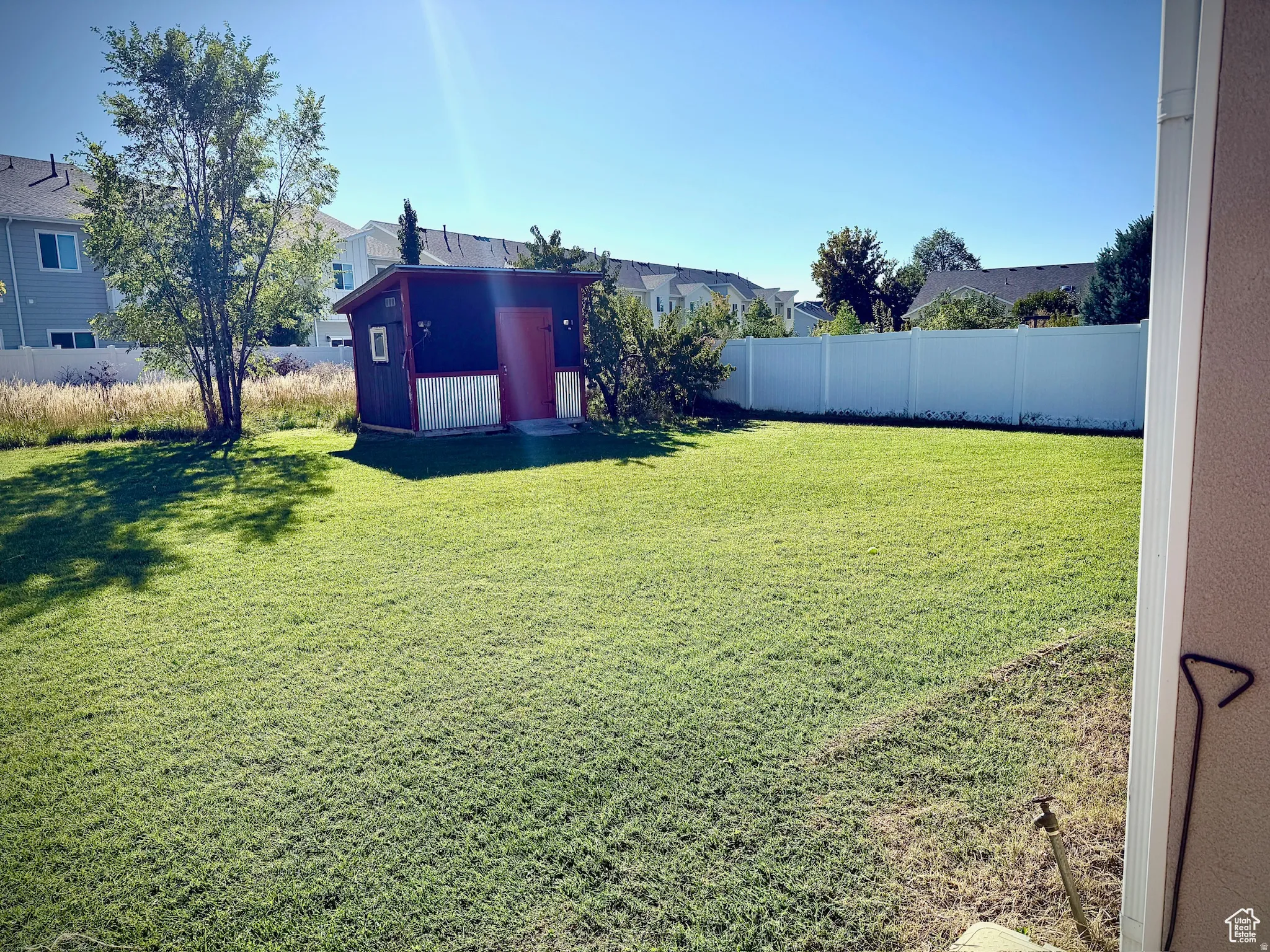 Fenced backyard featuring a residential view and a shed