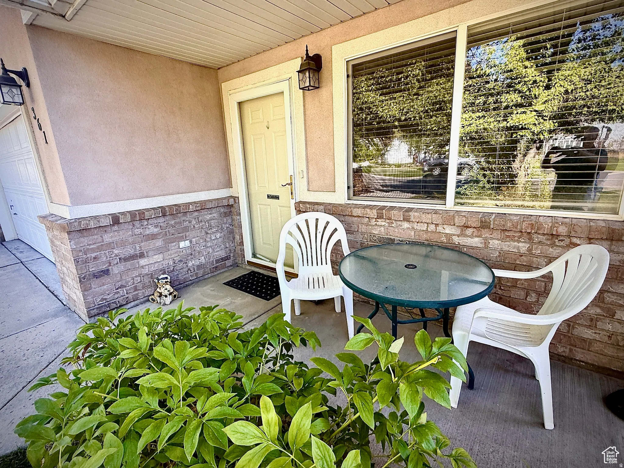 Doorway to property featuring a porch, stucco siding, and brick siding