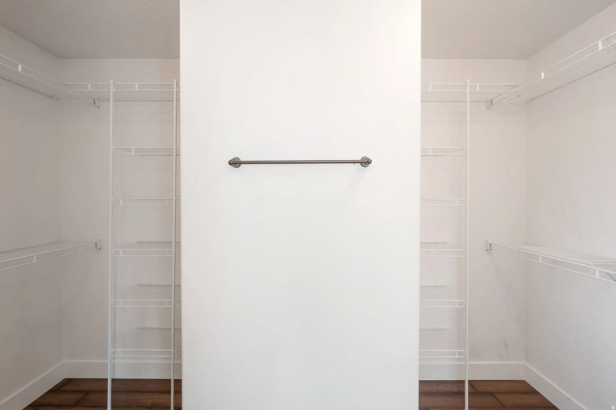 Walk-in closet featuring white wire shelving, hanging rods, and wood-finish flooring