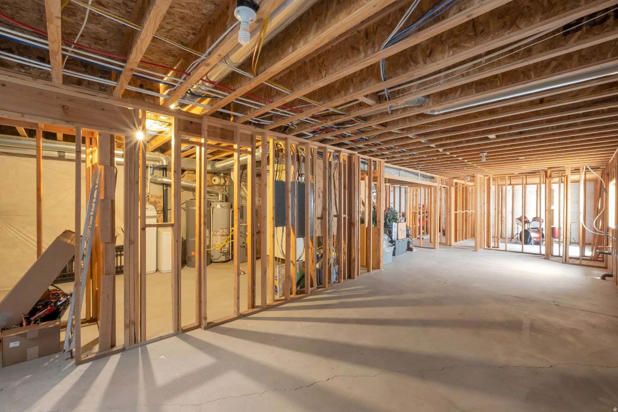 Unfinished basement featuring extensive framing, exposed ceiling joists, concrete flooring, and visible utility infrastructure including ductwork and plumbing