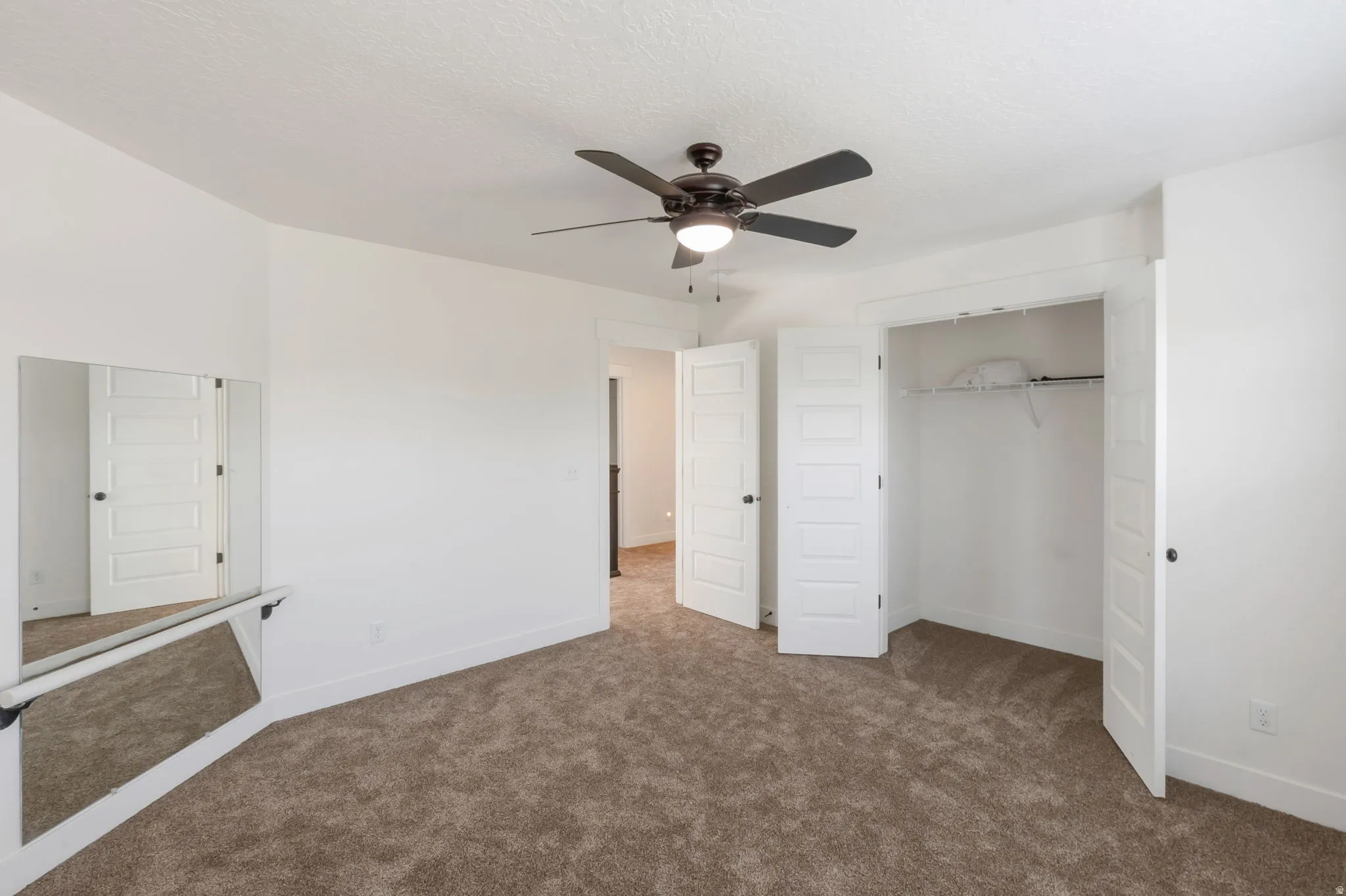 Carpeted room featuring a ceiling fan with integrated lighting, dual bifold closet doors, and white paneled interior doors