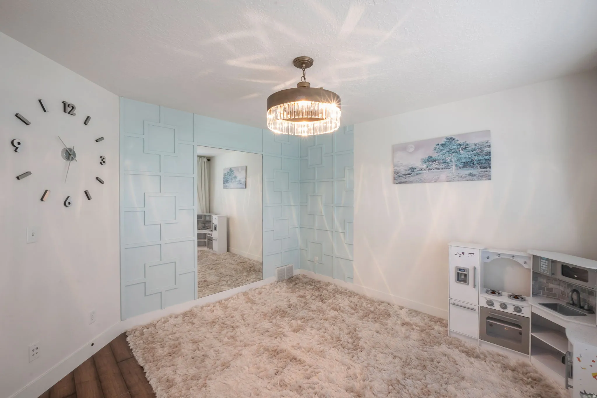 Recessed lighting illuminates a decorative ceiling fixture, soft wall-to-wall carpeting, and wood-finish flooring