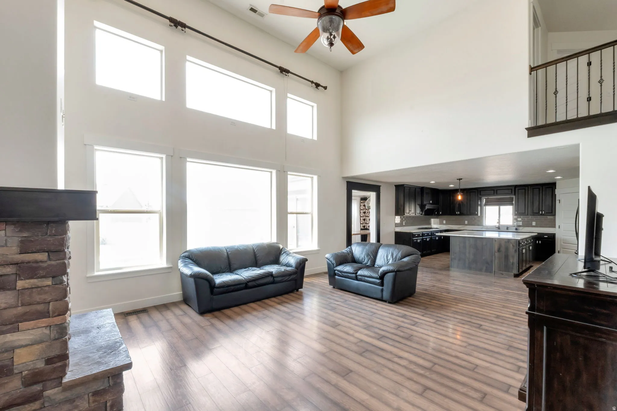 Spacious living area featuring wood-finish flooring and a stone-clad fireplace