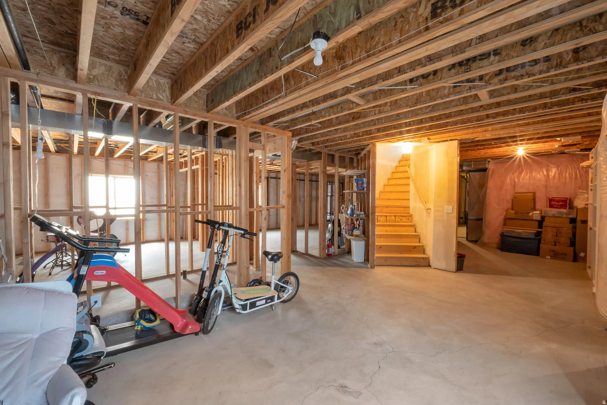 Spacious unfinished basement offering concrete flooring, exposed ceiling joists, and framed partition walls