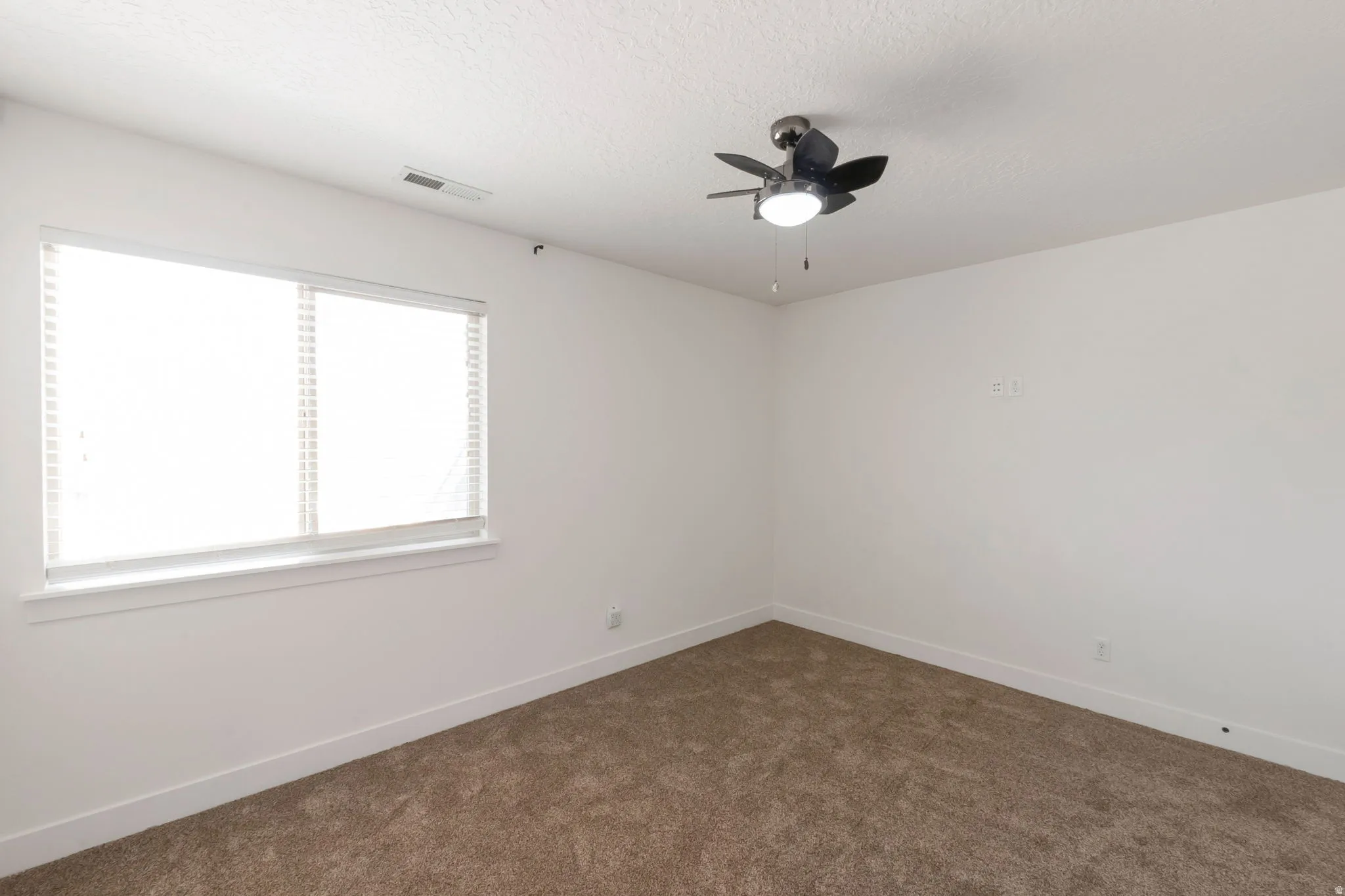 Carpeted room with a ceiling fan light fixture