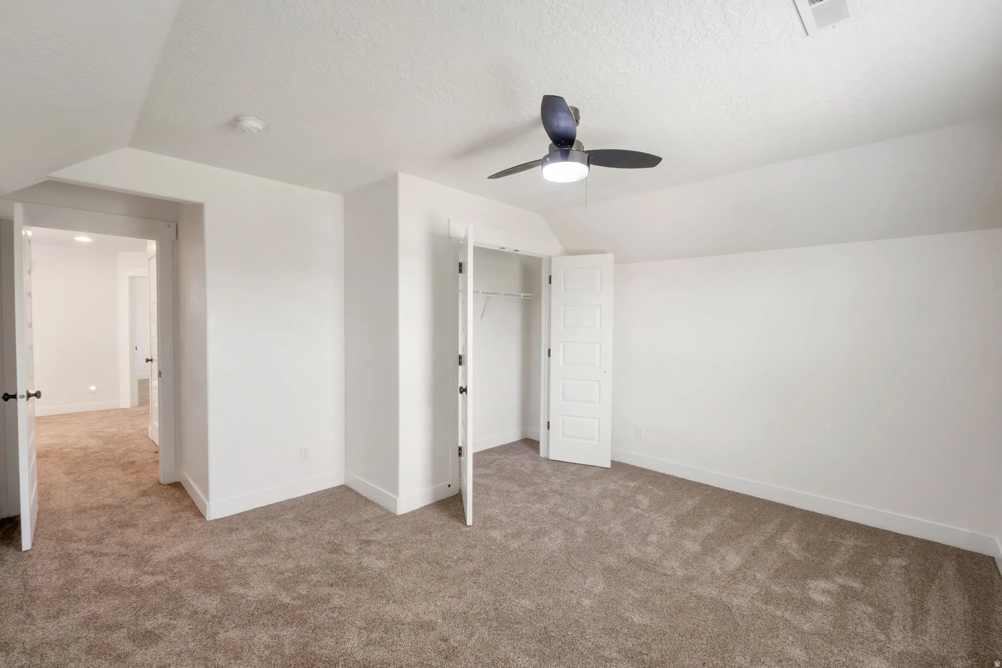 Carpeted room featuring a ceiling fan with integrated lighting, a built-in closet with panel doors, and neutral wall finishes