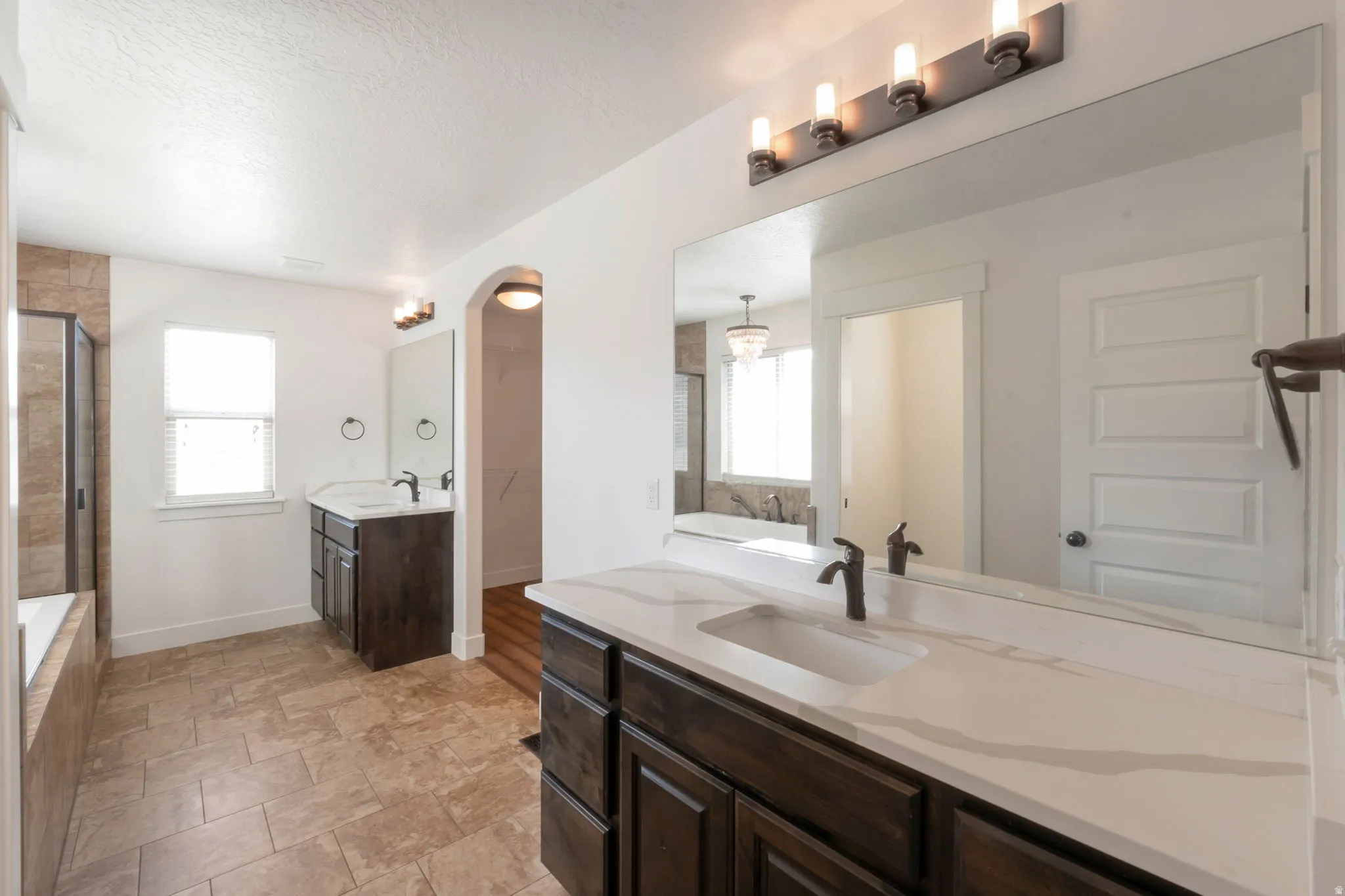 Bathroom featuring dual dark wood-finish vanities with light countertops, rectangular undermount sinks, and dark bronze fixtures