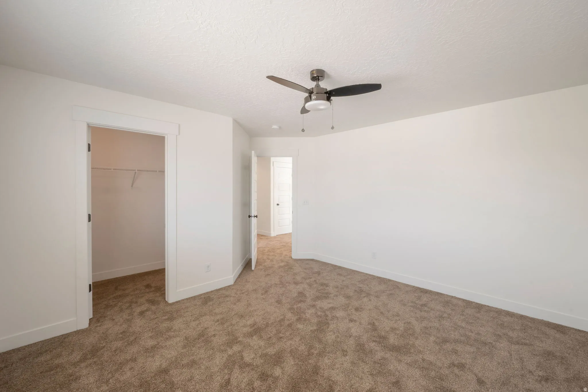 Spacious room featuring neutral carpeting, white walls, and a contemporary ceiling fan with integrated lighting