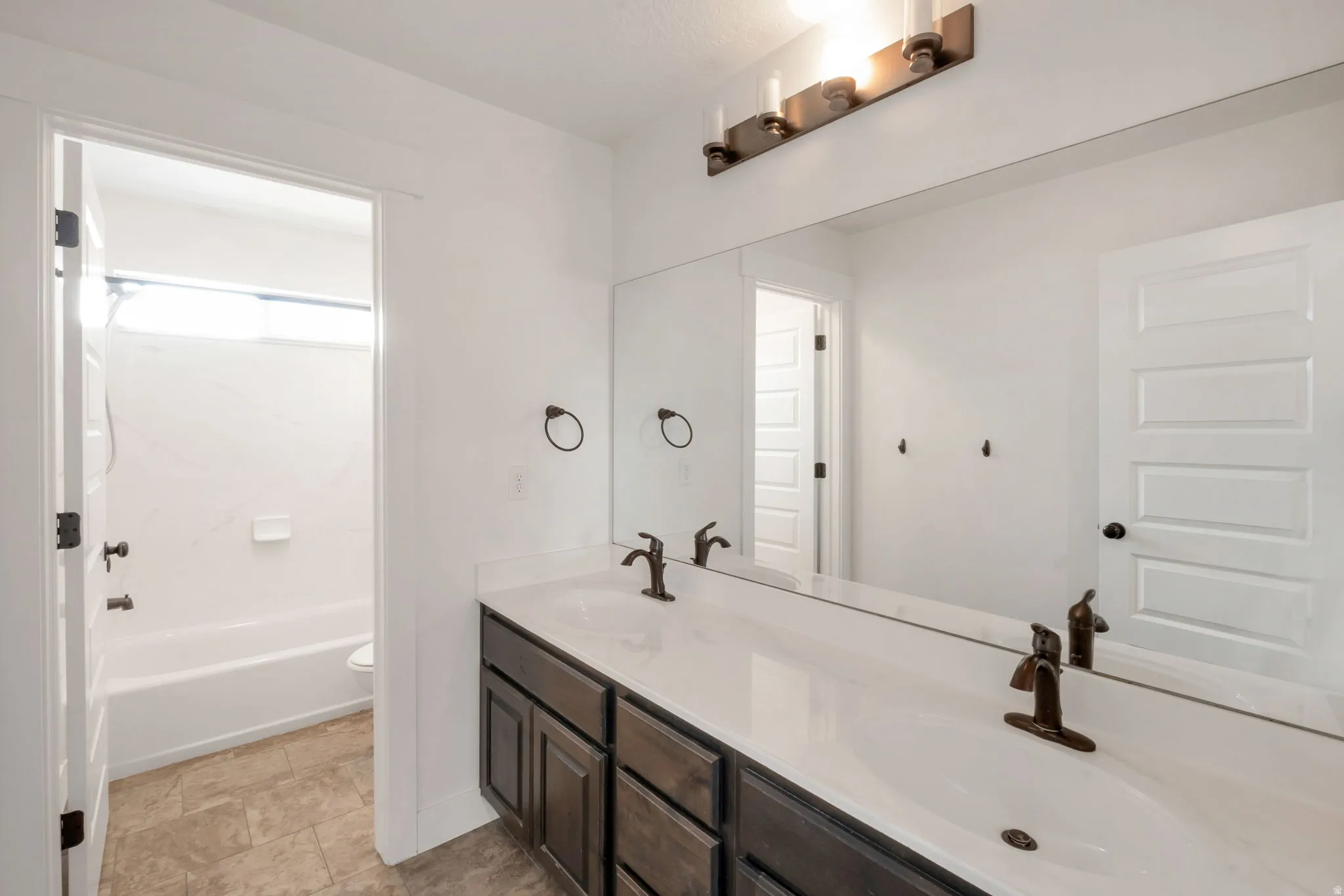 Bathroom featuring a double vanity with white countertops, dark wood-finish cabinetry, and oil-rubbed bronze fixtures