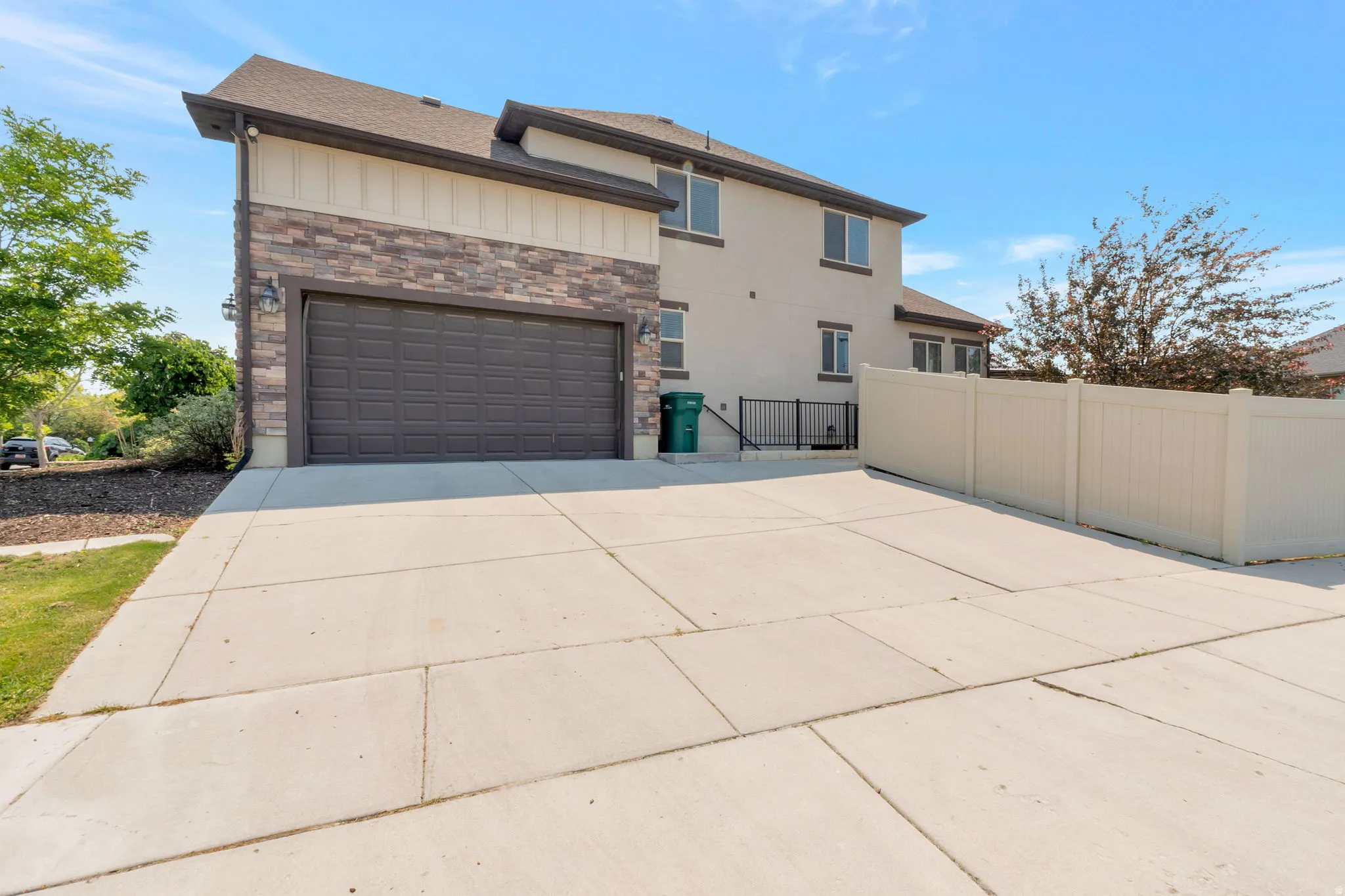 Two-story stucco home with a stone facade accent, featuring a two-car garage with an overhead door