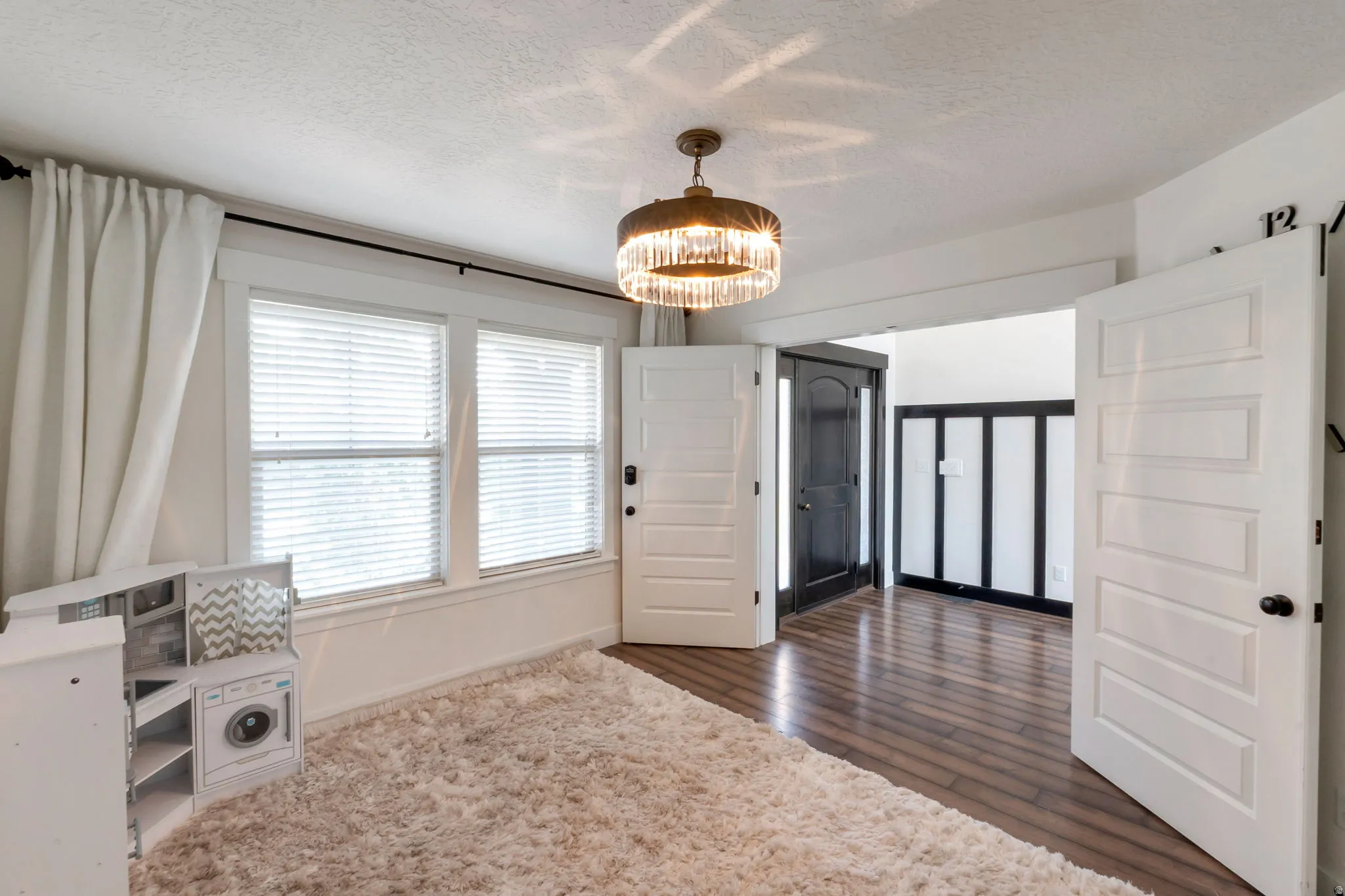 Bright room featuring wood-finish flooring, a tiered crystal chandelier, and white paneled doors