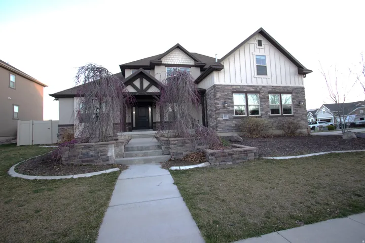 View of front of property with stone siding, a front lawn, and board and batten siding
