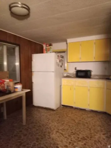 Kitchen featuring freestanding refrigerator, black microwave, and light countertops