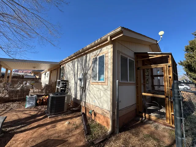 Exterior view featuring beige siding, white-framed windows, and a covered patio area