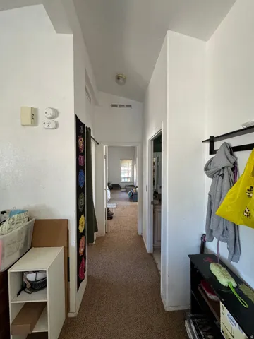 Carpeted hallway featuring white walls, a vaulted ceiling, and recessed lighting