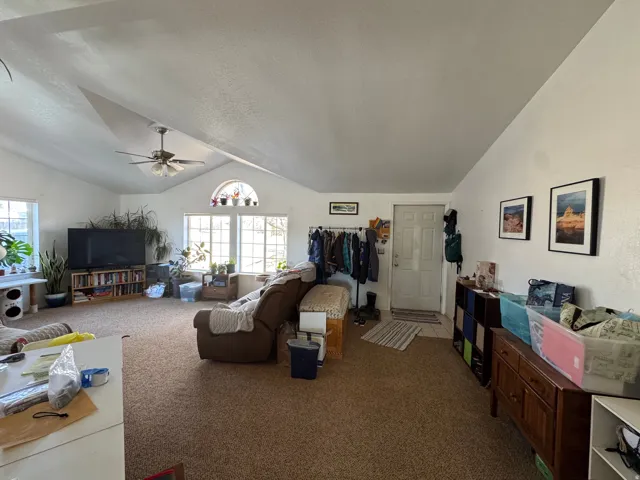 Open-concept living area featuring a vaulted ceiling and an arched transom window