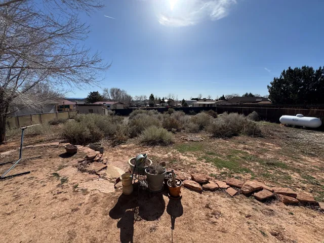Expansive rear yard with natural landscaping, a partial stone patio, and perimeter fencing