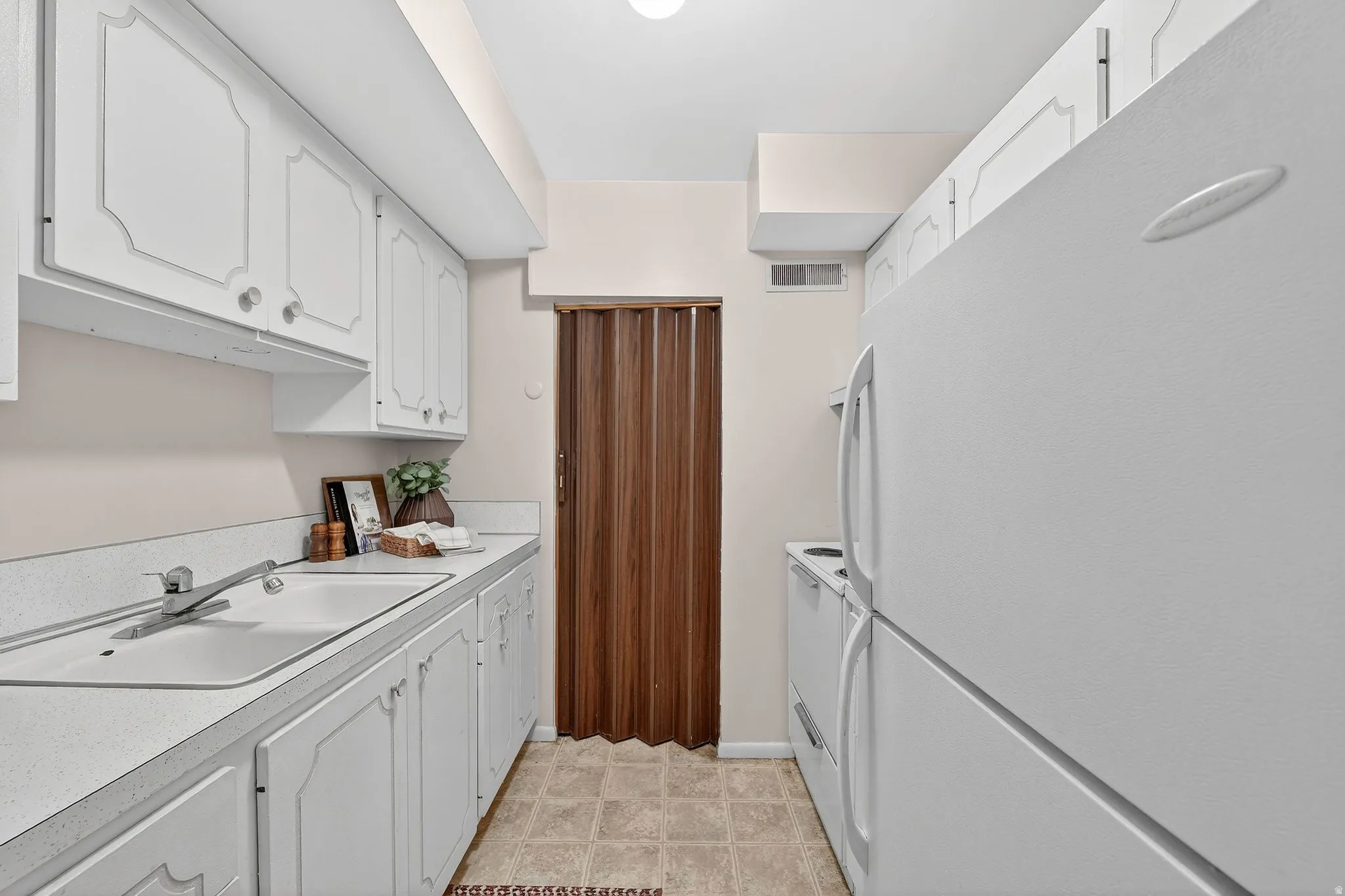 Kitchen featuring white appliances, white cabinetry, and light countertops