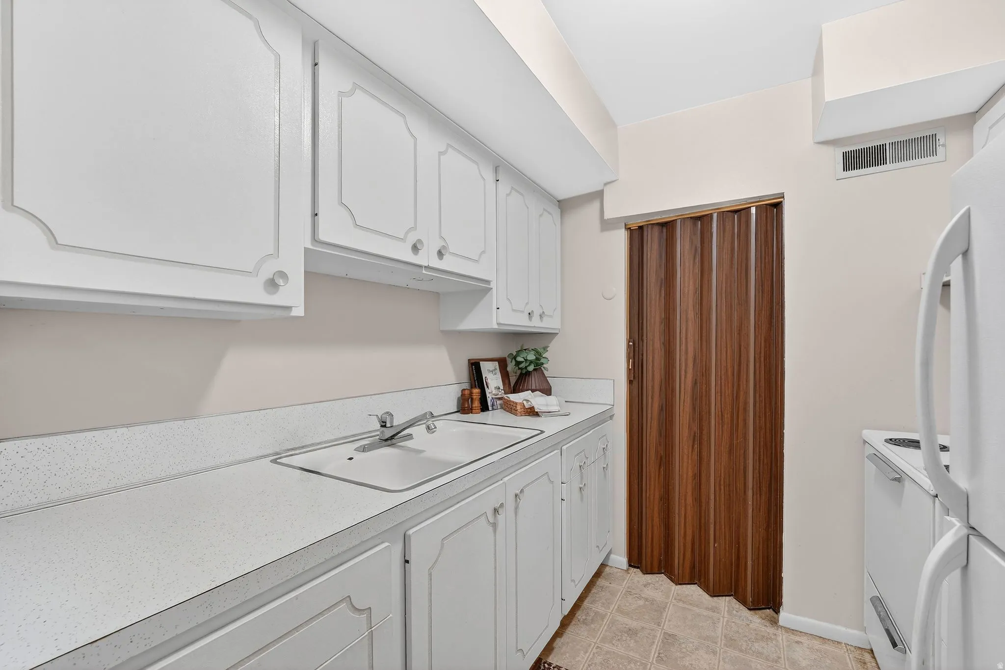 Kitchen featuring white cabinetry, light countertops, and white appliances
