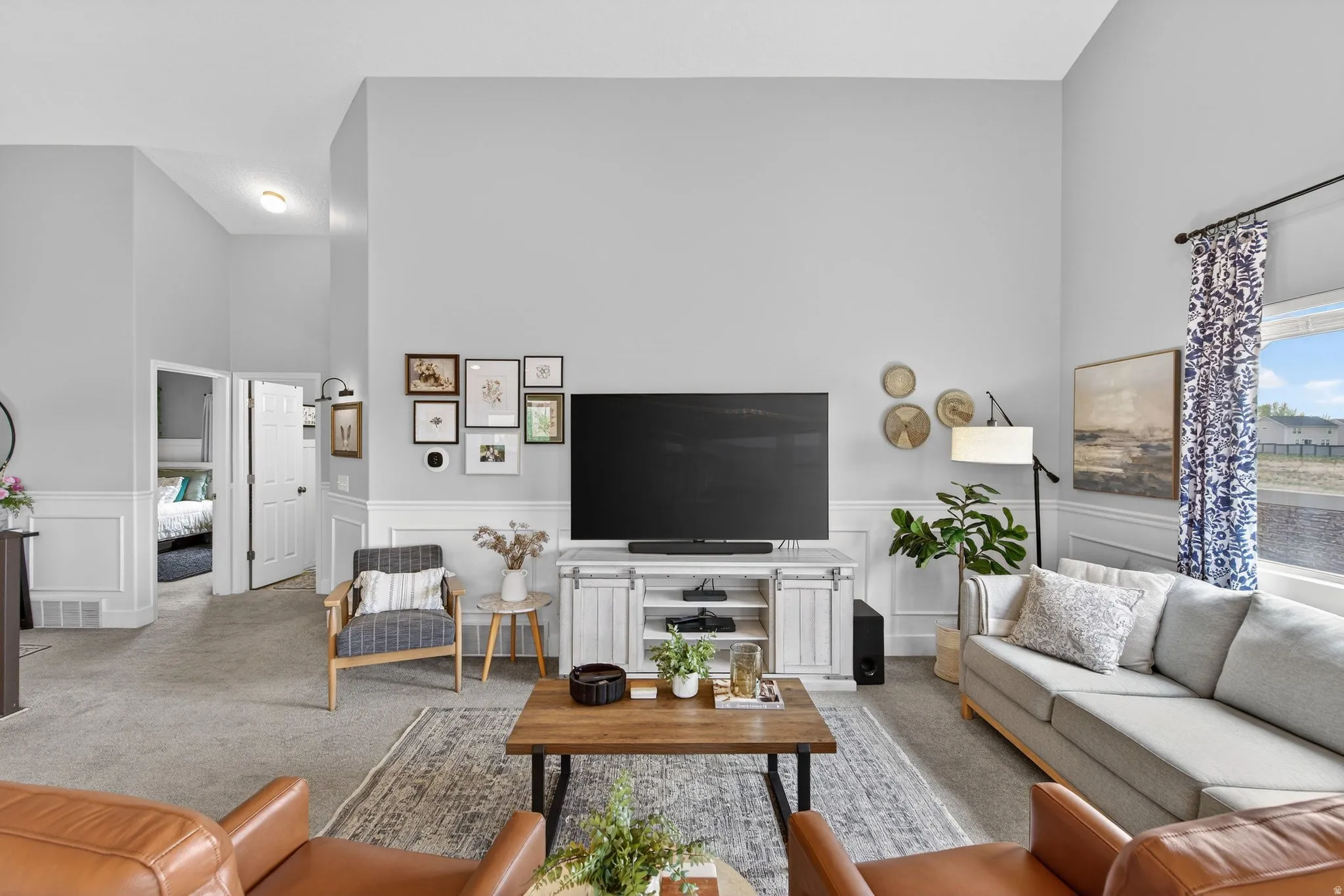 Living area with a high ceiling, carpet floors, wainscoting, and a decorative wall
