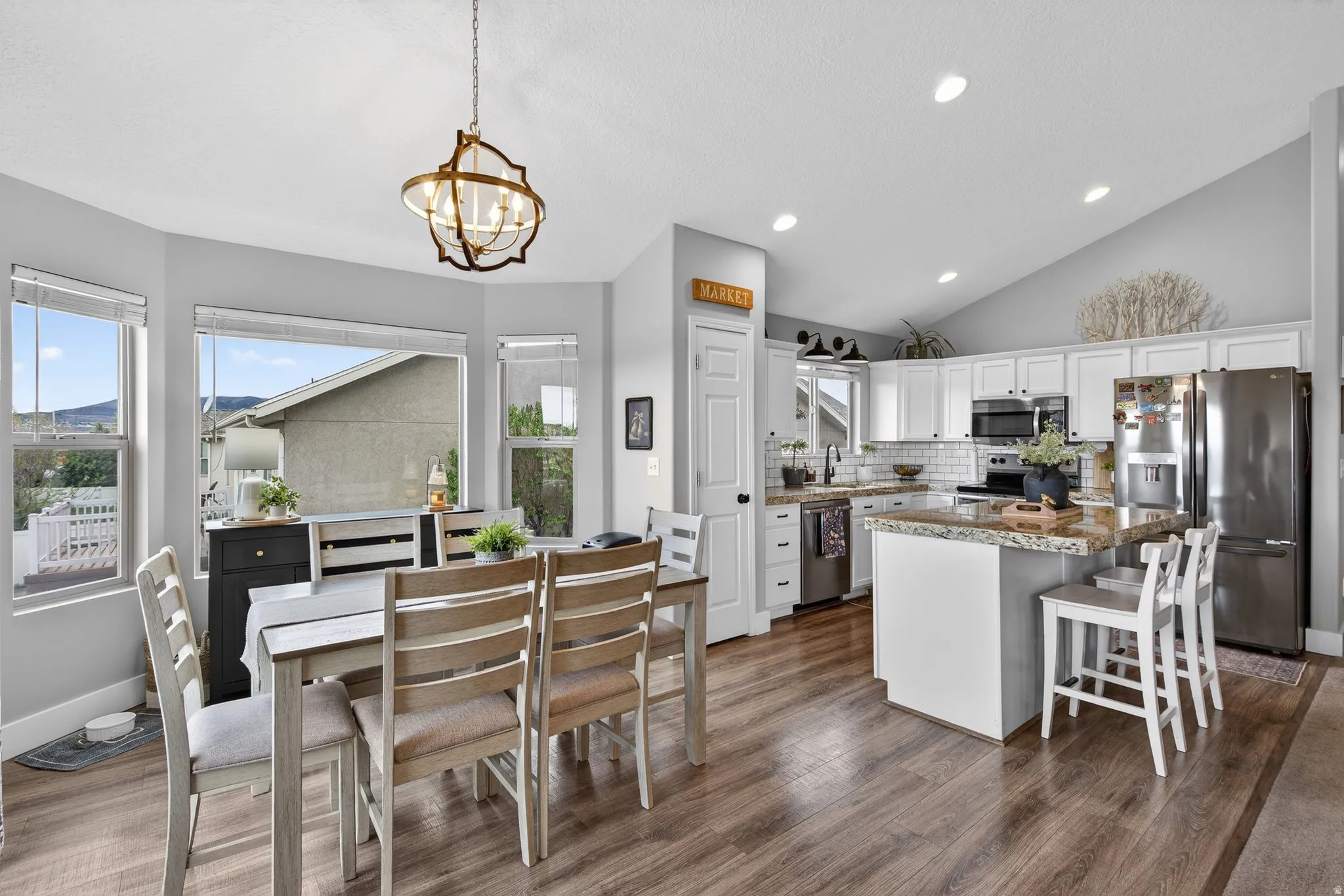Kitchen with stainless steel appliances, white cabinets, a kitchen island, a breakfast bar, and tasteful backsplash