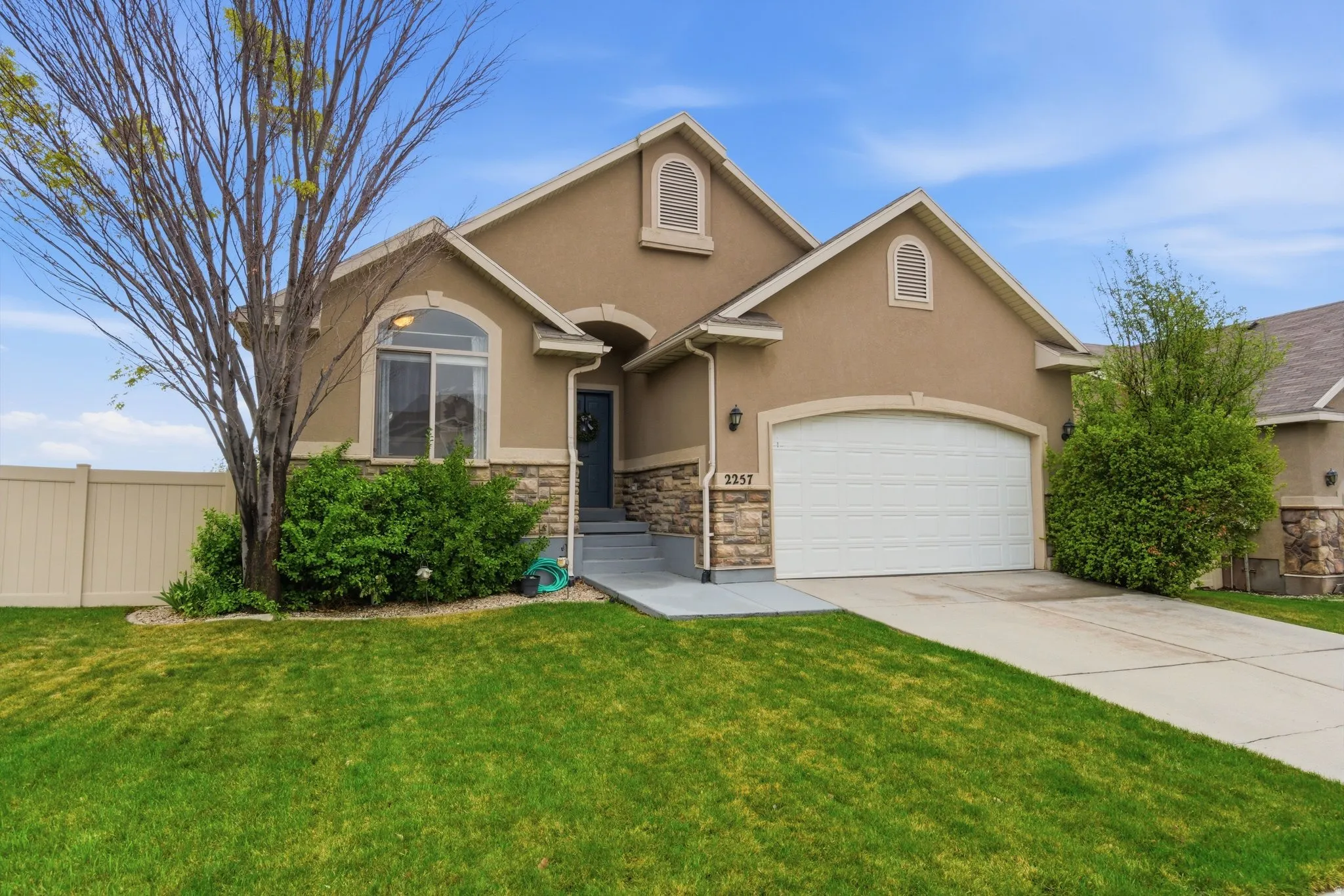 View of front of home with stucco siding, concrete driveway, a garage, and stone siding