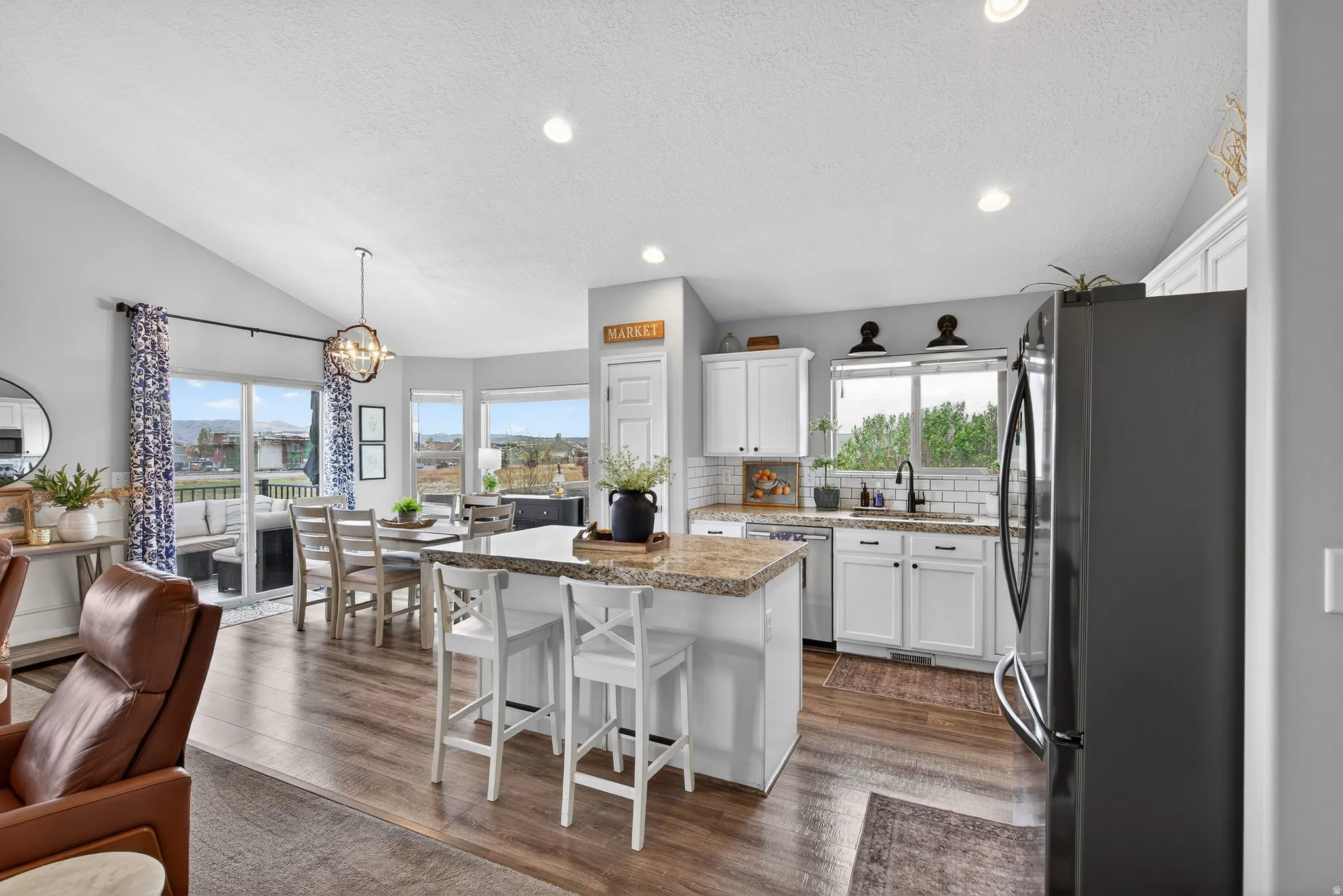 Kitchen featuring stainless steel appliances, white cabinetry, a center island, hanging lights, and a kitchen bar