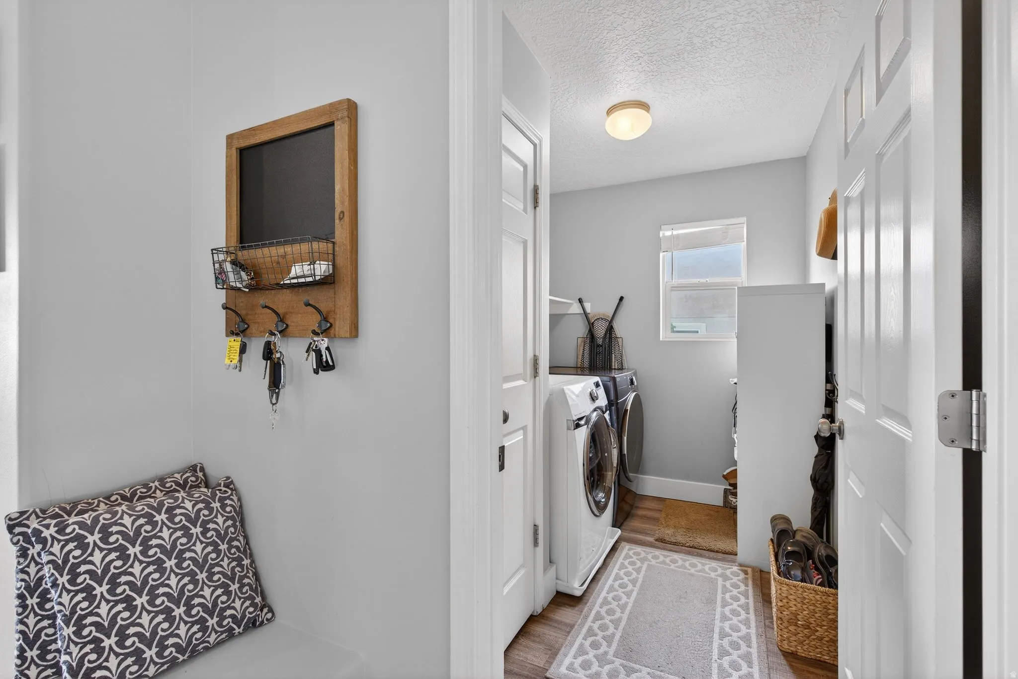 Laundry room featuring a textured ceiling, light wood finished floors, and independent washer and dryer