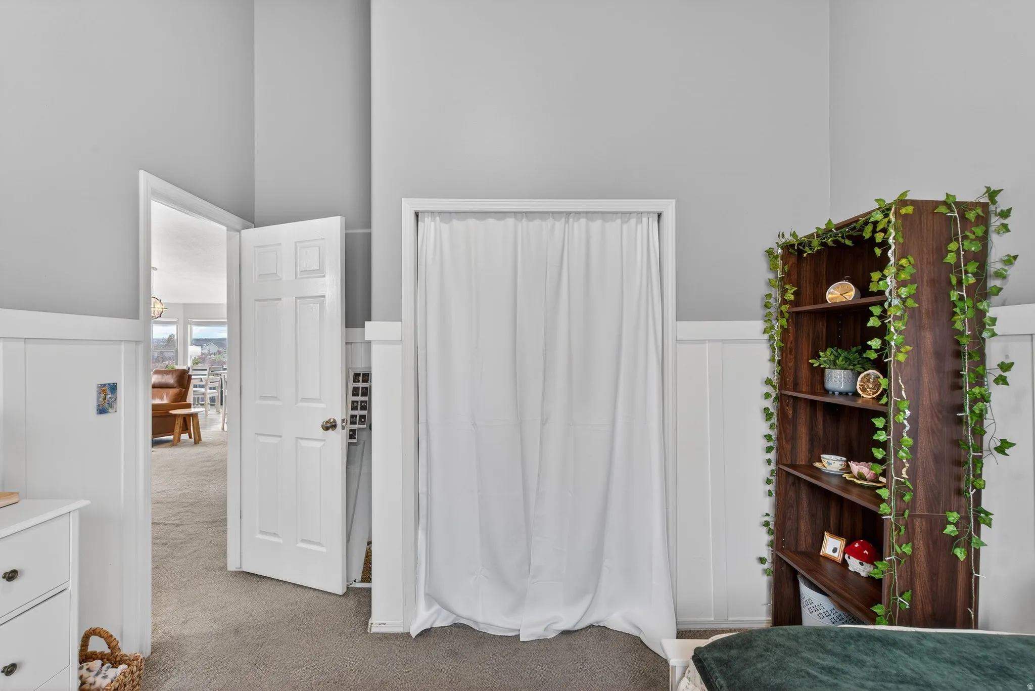 Bedroom with a wainscoted wall, light carpet, and a decorative wall