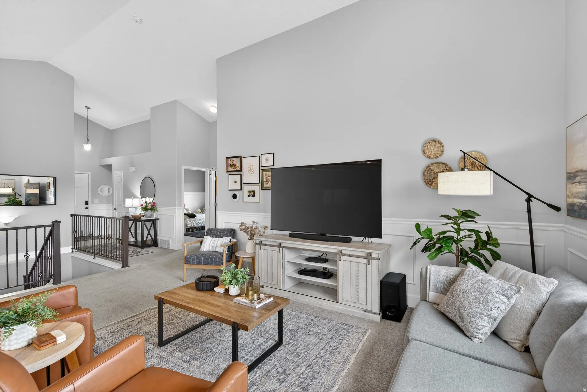 Carpeted living area featuring lofted ceiling and wainscoting