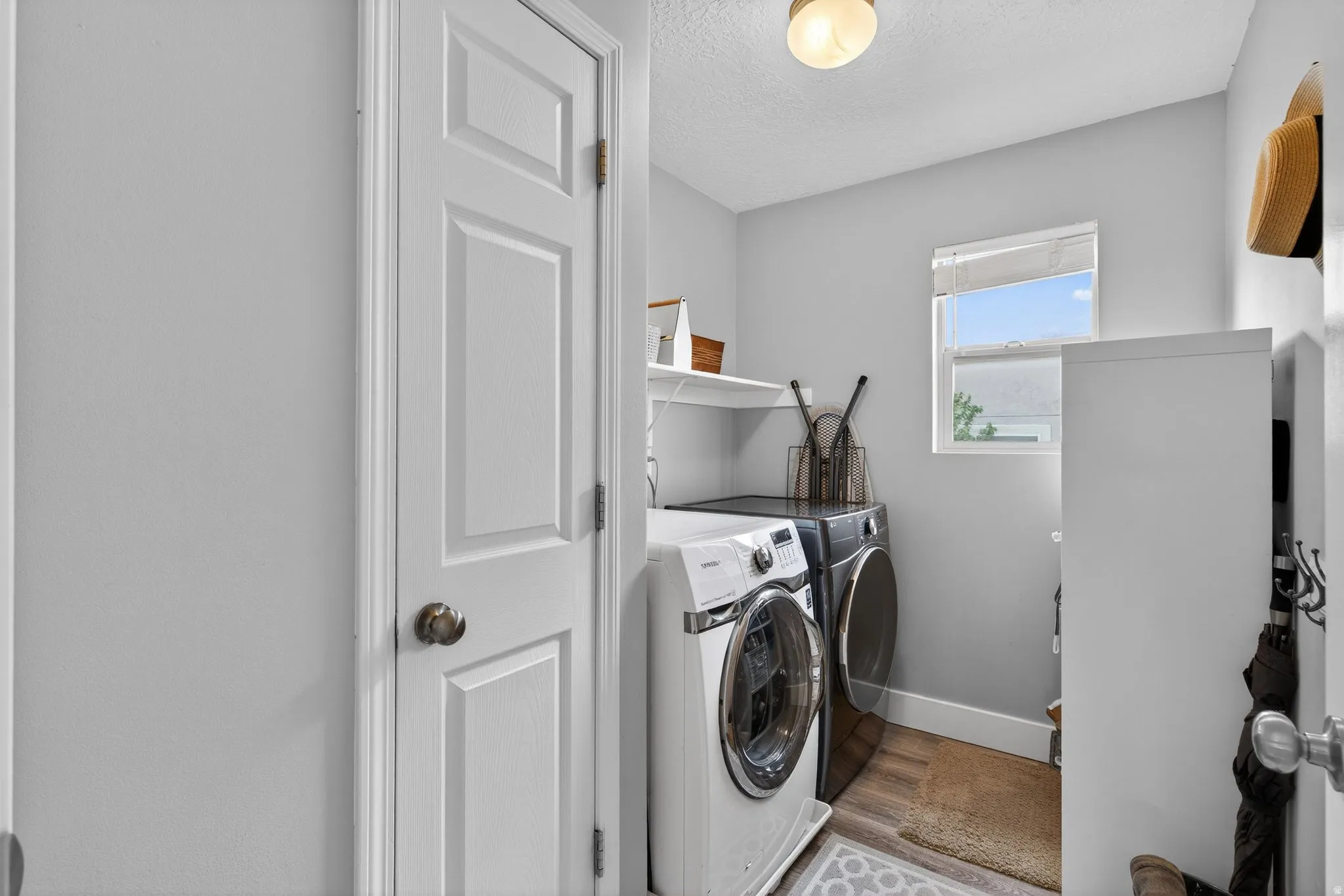 Laundry room with independent washer and dryer, a textured ceiling, and light wood-style flooring