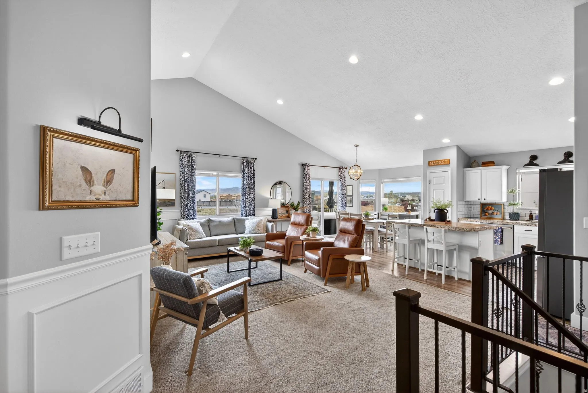 Living room with vaulted ceiling, a wainscoted wall, recessed lighting, light carpet, and a decorative wall