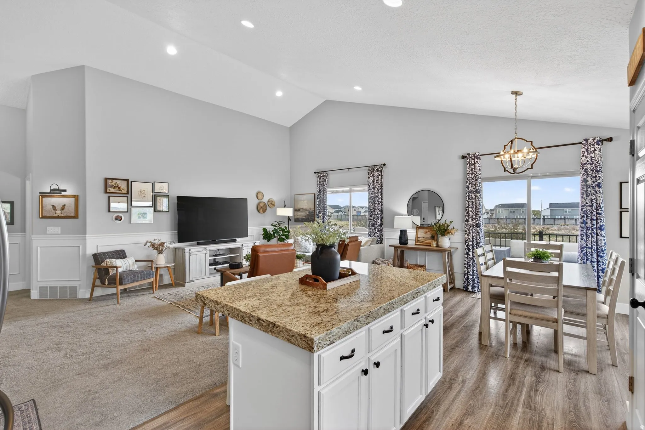 Kitchen with open floor plan, white cabinetry, vaulted ceiling, a center island, and light countertops