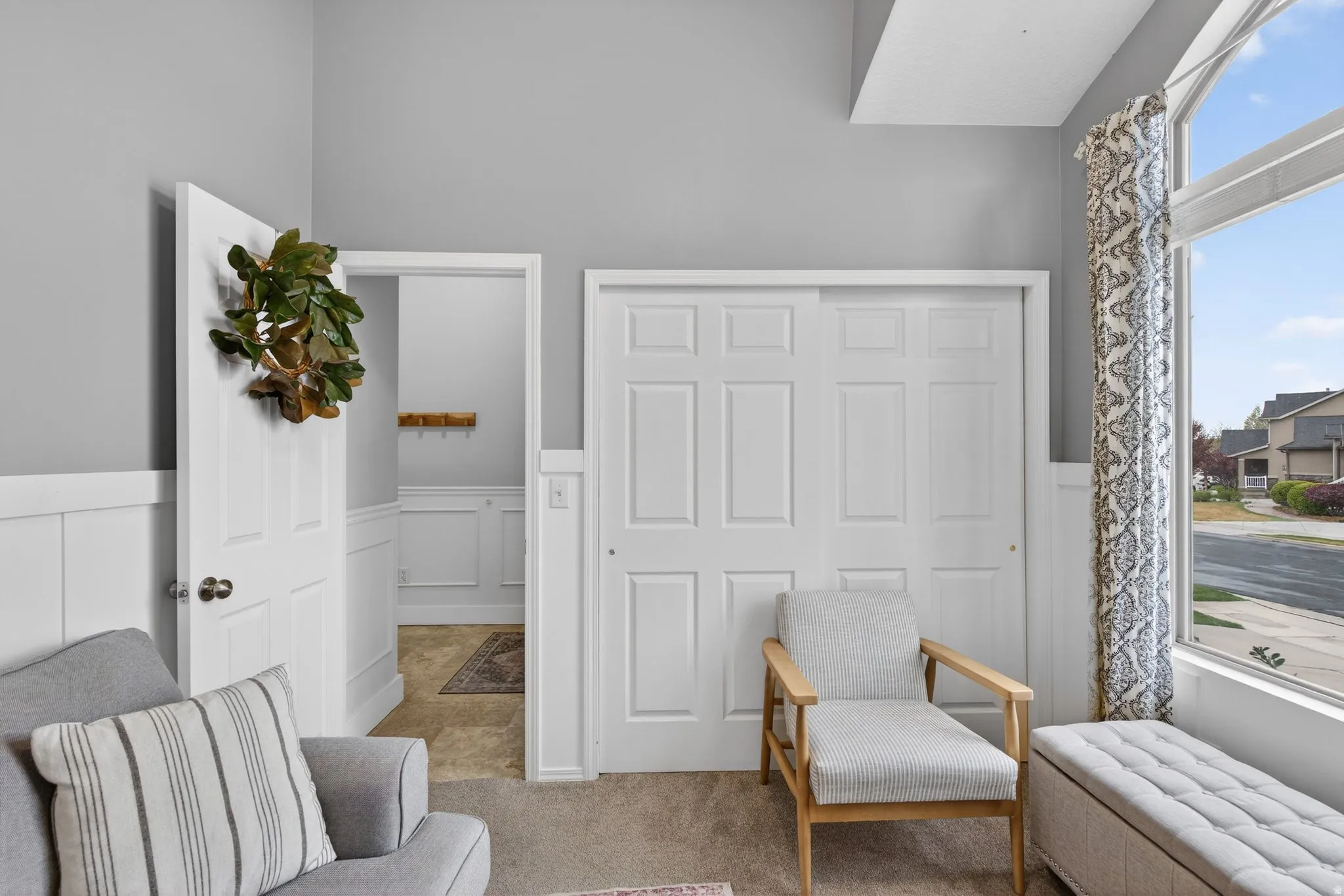 Sitting room featuring wainscoting, a decorative wall, and carpet