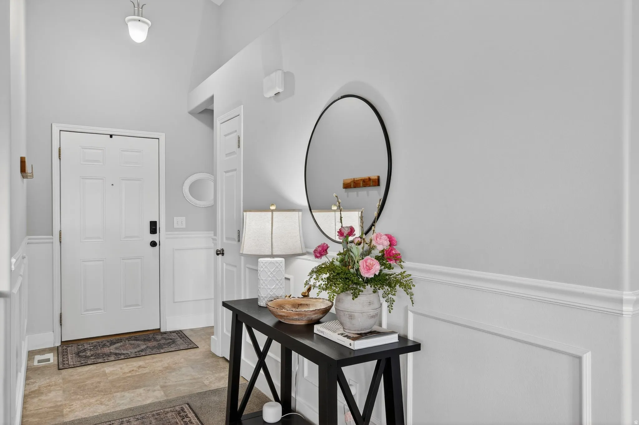 Foyer with a decorative wall, a wainscoted wall, and a high ceiling