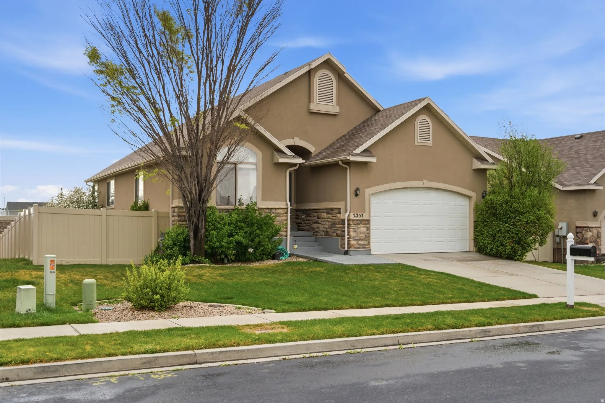 View of front of property featuring stucco siding, concrete driveway, a garage, and stone siding