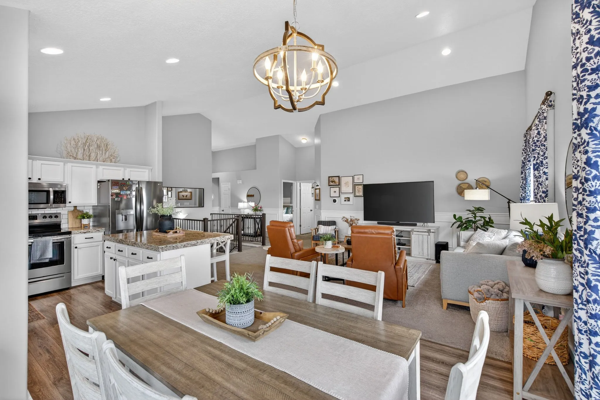 Dining room featuring vaulted ceiling, suspended lighting, light wood-style flooring, and a wainscoted wall