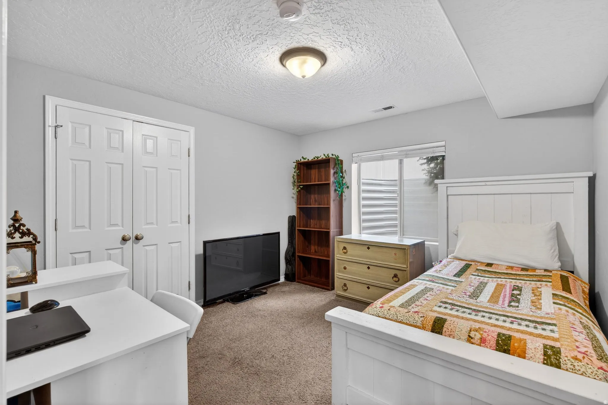 Bedroom with light carpet, a closet, and a textured ceiling