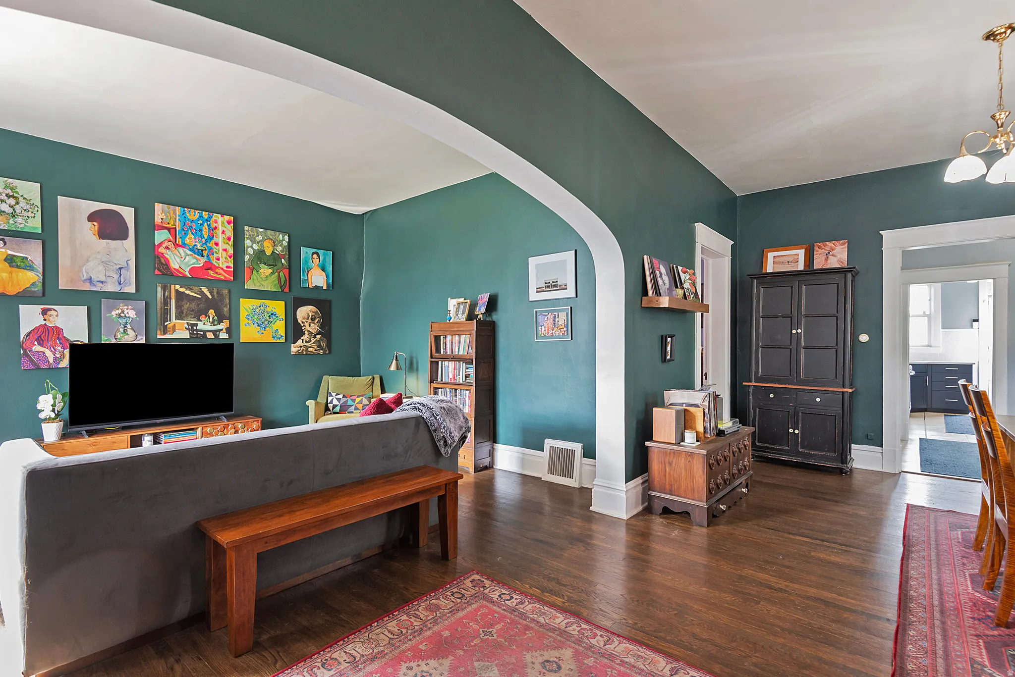 Living area featuring arched walkways, dark wood-style floors, and a chandelier