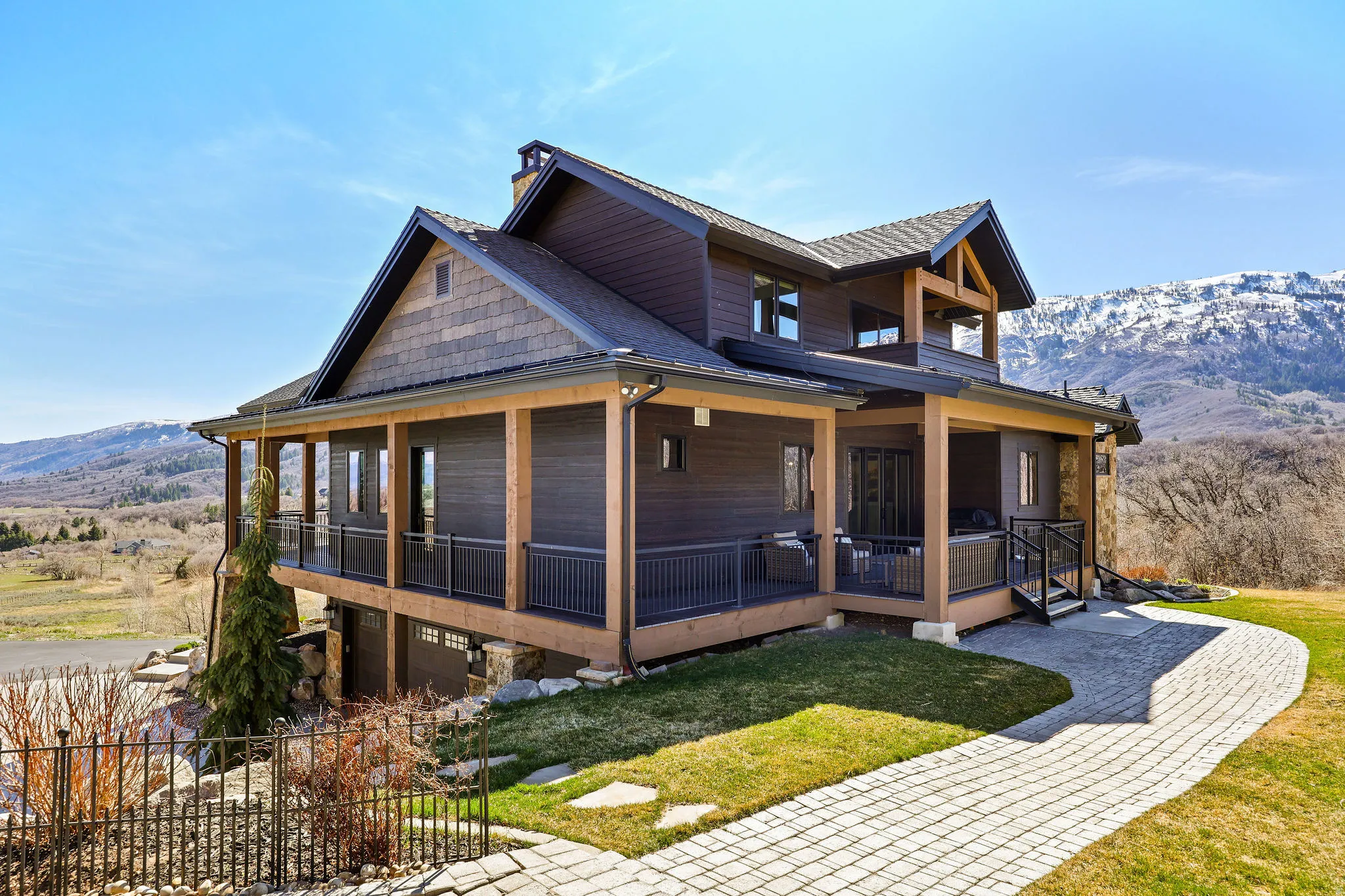 View of front facade featuring a mountain view, a porch, a front lawn, roof with shingles, and an attached garage