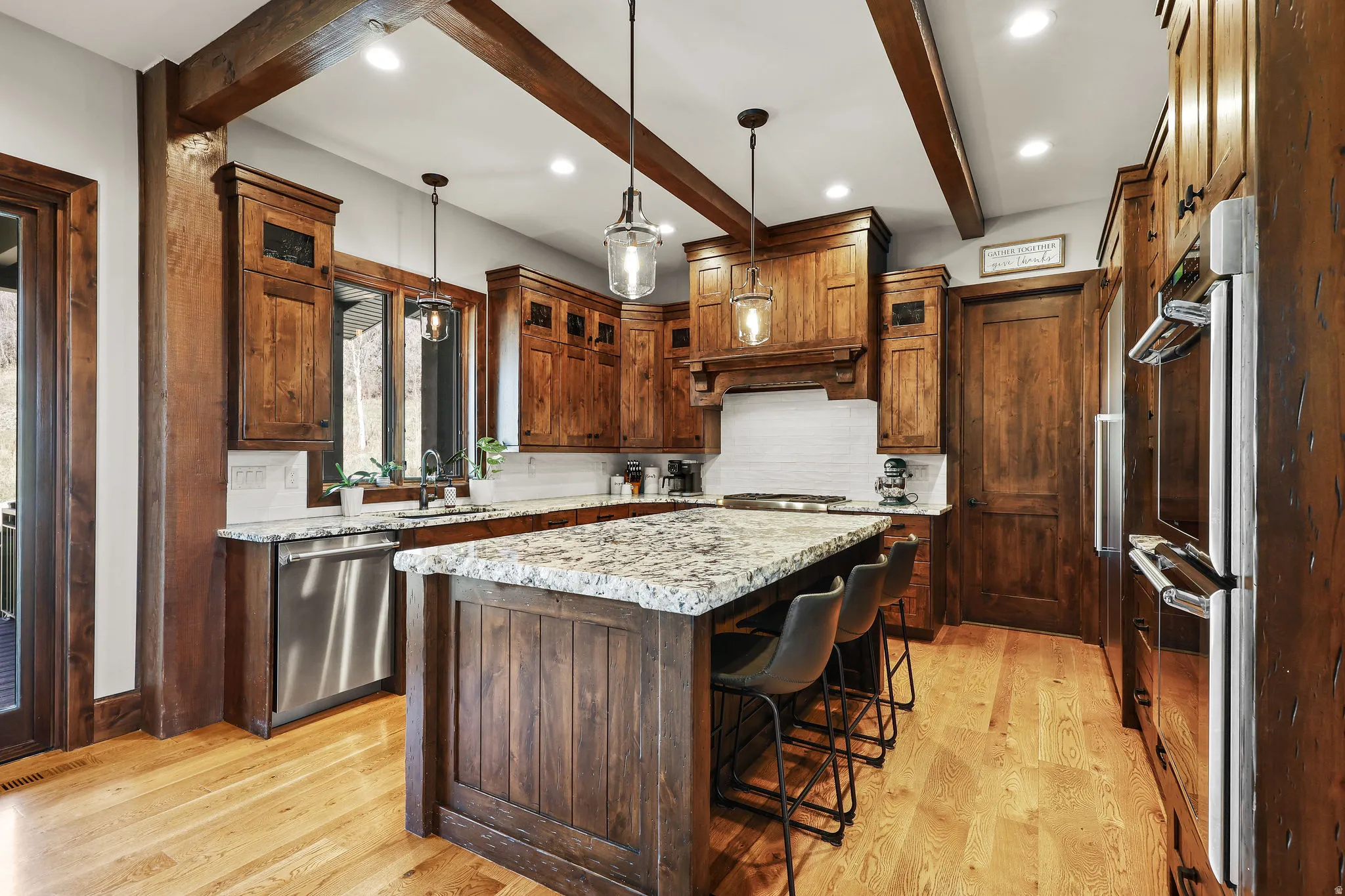 Kitchen featuring stainless steel appliances, a kitchen island, light wood-style floors, a kitchen bar, and hanging light fixtures