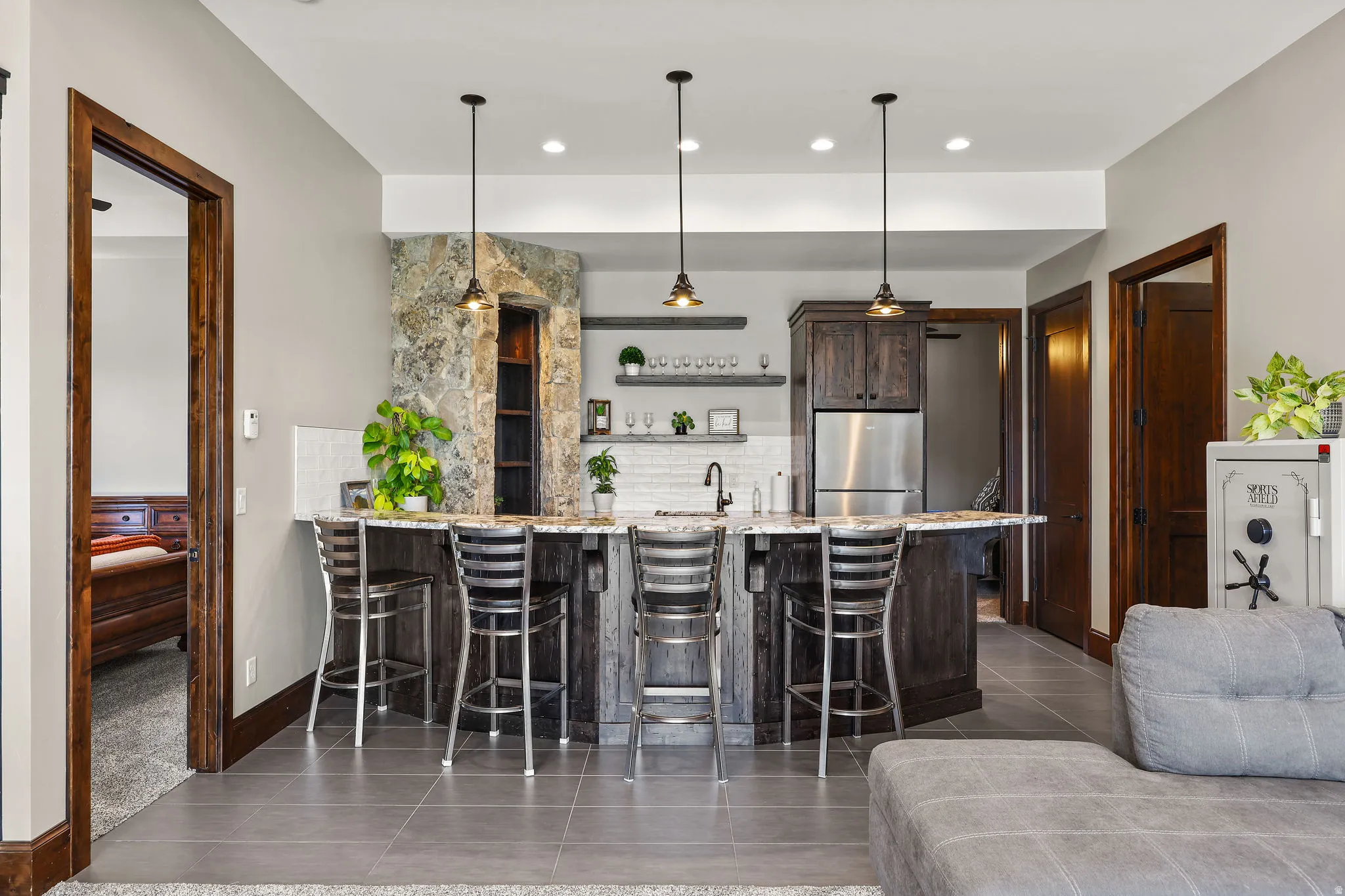 Kitchen with a peninsula, light stone countertops, a breakfast bar area, dark wood finish cabinetry, and dark tile patterned flooring
