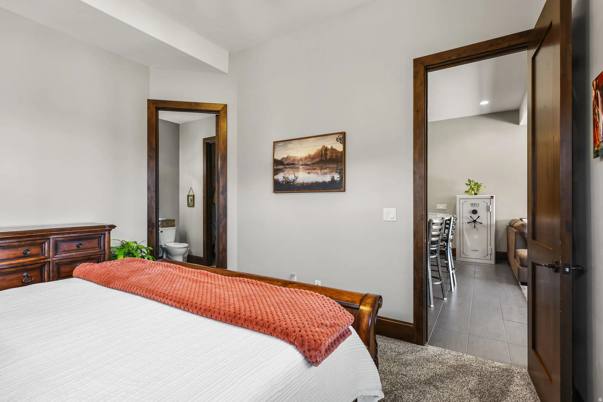 Bedroom featuring connected bathroom, light carpet, and light tile patterned flooring