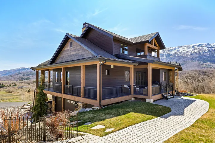 View of front facade featuring a mountain view, a porch, a front lawn, roof with shingles, and an attached garage