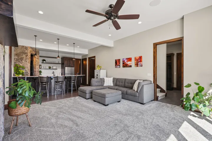 Living room with beam ceiling, bar with sink, recessed lighting, and a ceiling fan